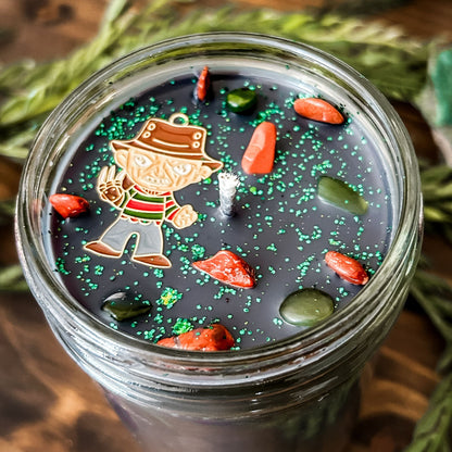 A black Halloween candle that is decorated with a horror movie charm, spooky crystals, and gothic glitter.