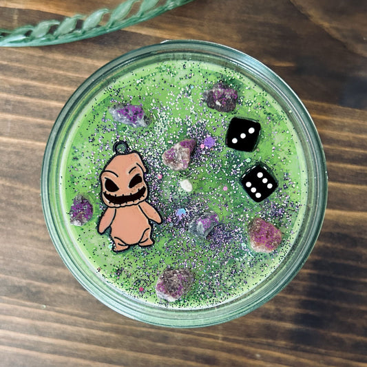 A Halloween candle that is decorated with a nightmare before Christmas oogie boogie, spooky crystals, and gothic glitter.