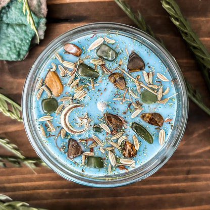 Light blue intention Litha candle that is decorated with crystals, flowers, and magic glitter to celebrate summer solstice. The candle is decorated to represent abundance, growth, nature, and pagan rituals.