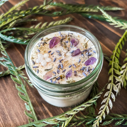 Natural soy intention candle that is decorated with a white flower, amethyst crystals. lavender, chamomile, and glitter for healing, anxiety relief, and calm energy.