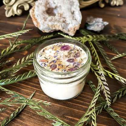 Natural soy intention candle that is decorated with a white flower, amethyst crystals. lavender, chamomile, and glitter for healing, anxiety relief, and calm energy.