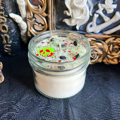 A Halloween candle decorated with a spooky melting apple charm, witchy crystals, and gothic glitter.
