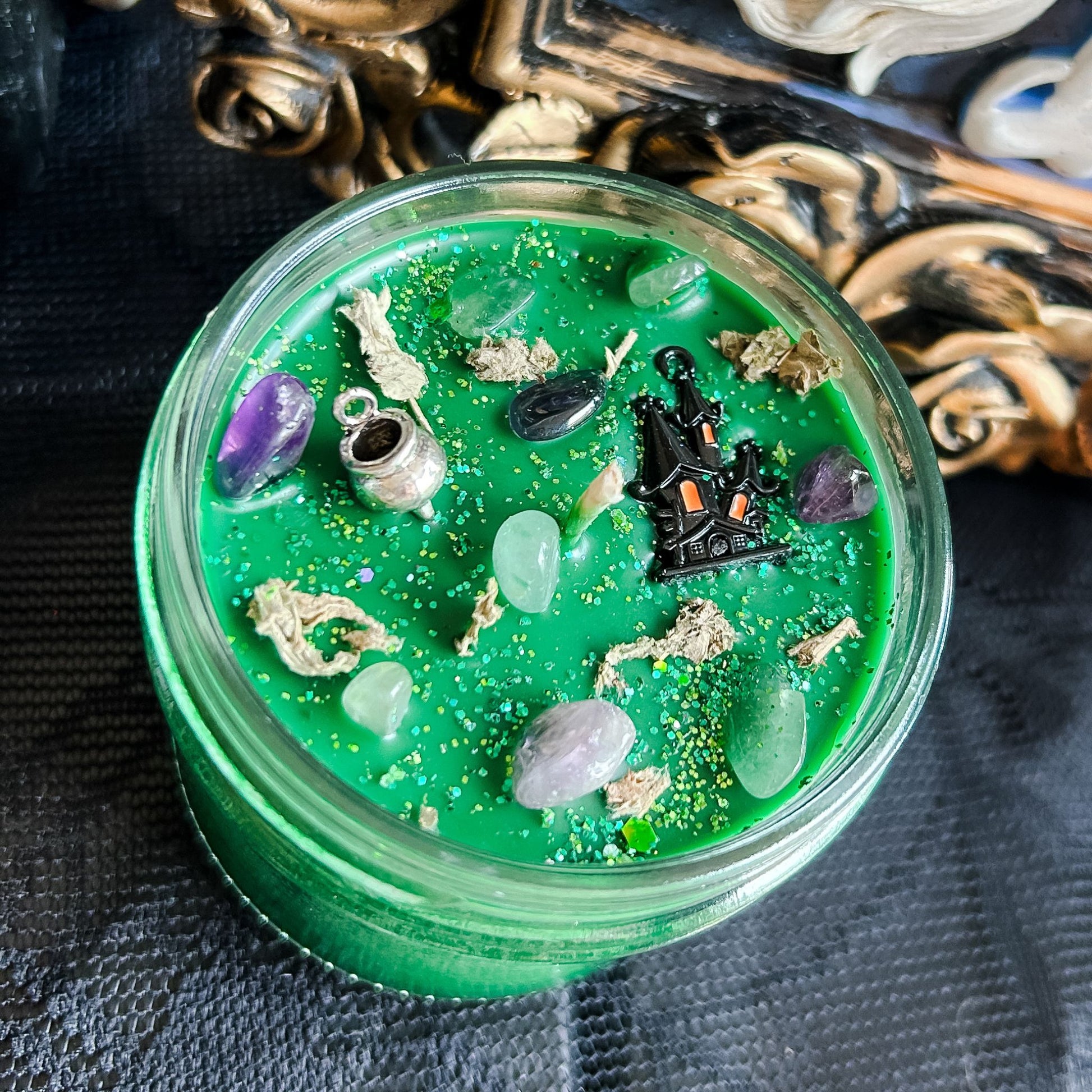 Spooky Halloween candle with witches' brew cauldron design, green wax, and flickering flame, perfect for fall decor and haunted house ambiance.