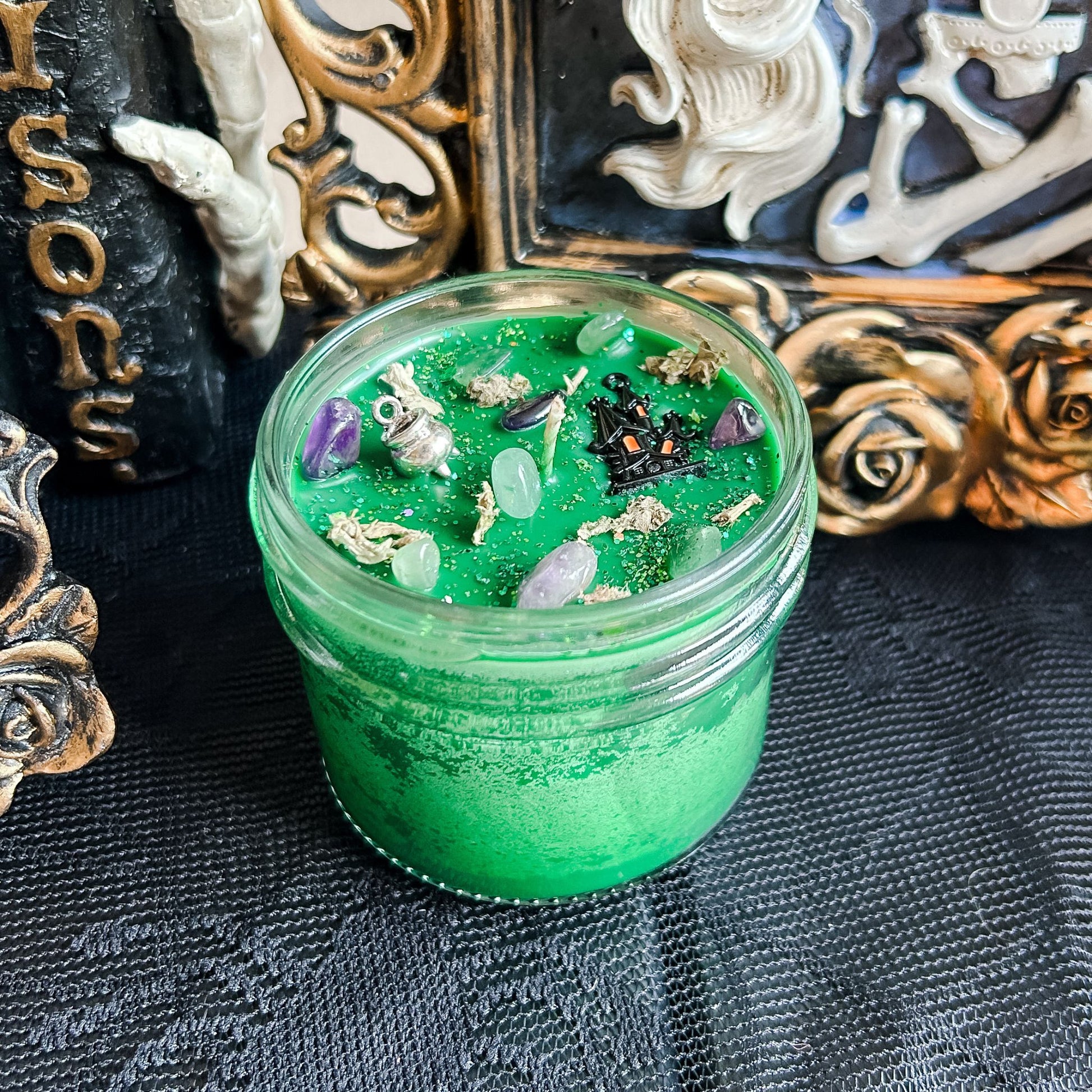 Spooky Halloween candle with haunted house and cauldron design, green wax, and flickering flame, perfect for fall decor and haunted house ambiance.