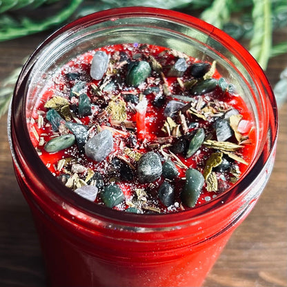 Red intention pagan candle that is decorated with witchy crystals, flowers, and magic glitter to represent Winter Solstice and Yule.