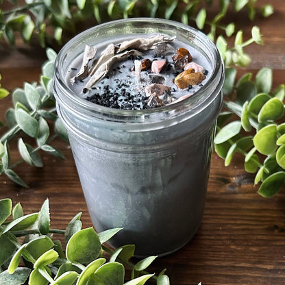Silver intention candle that is decorated with gold tigers eye crystal, smokey quartz crystal, rhodonite crystal, protection salt, white sage, and witchy glitter to manifest goddess energy and power.
